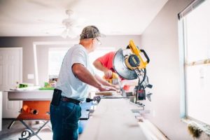 two man using saw to cut wood while doing home improvement