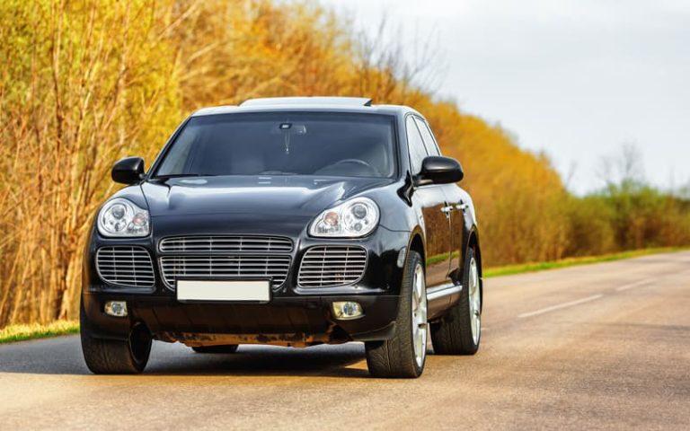 Black luxury car at byroad in autumn time