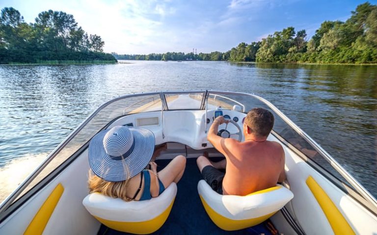 Young couple driving yellow speed boat