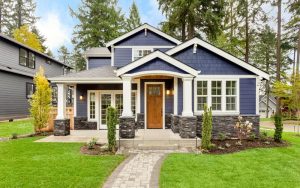 Beautiful exterior of newly built luxury home. Yard with green grass and walkway lead to ornately designed covered porch and front entrance.