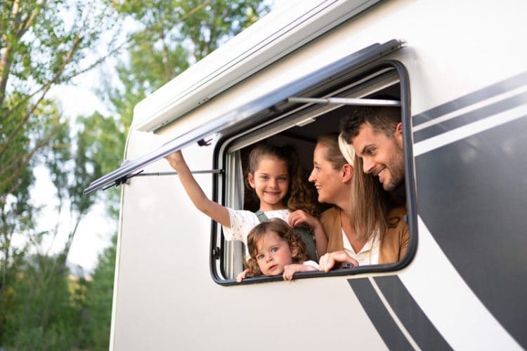 young family looking out a window of their recreational vehicle while camping