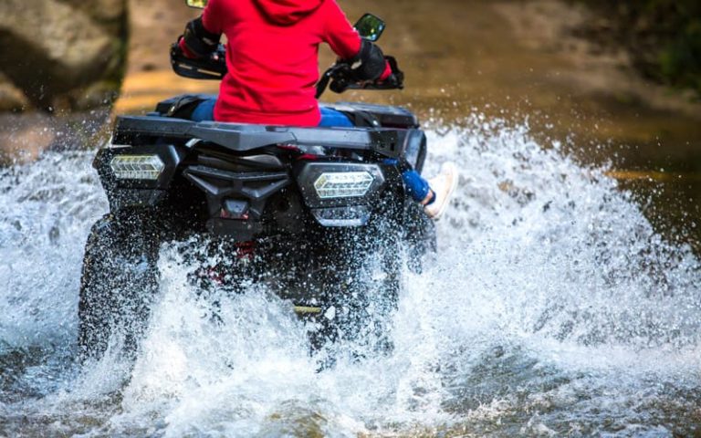 The girl driving an ATV through the river Spree.