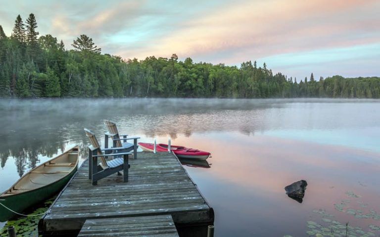 Canoe and kayak moored to a cottage dock at dawn - Ontario, Canada