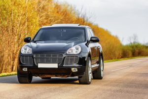 Black luxury car at byroad in autumn time