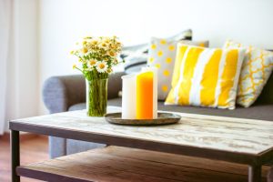 Modern wooden coffee table and cozy sofa with pillows. Living room interior and home decor concept